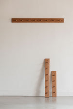 Three sizes of the wooden Shaker peg rack from Chilton Furniture, one hung on the wall, two leaning on the wall