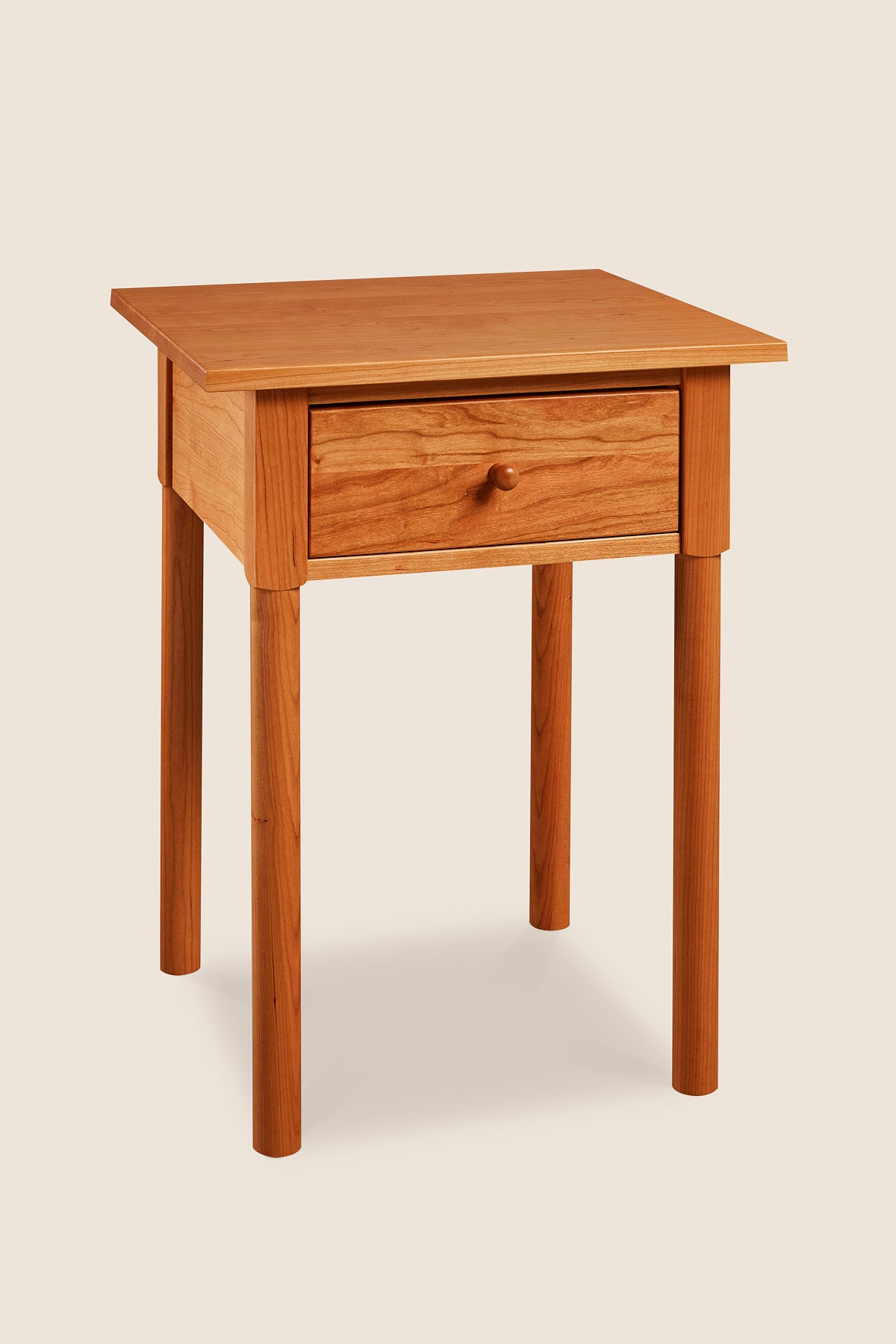 Modern interpretation of a classic Shaker style nightstand with one drawer and rounded legs, in solid cherry wood